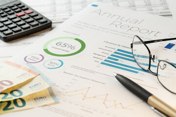 Mockup financial charts report sheet with visible pen, calculator, eyeglasses and euro banknotes. Accounting, business, finance, tax and office concepts.