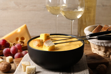 Tasty cheese fondue, snacks and wine on wooden table
