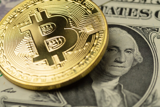 Golden Bitcoin cryptocurrency coin covering the image of George Washington on one US Dollar banknote
