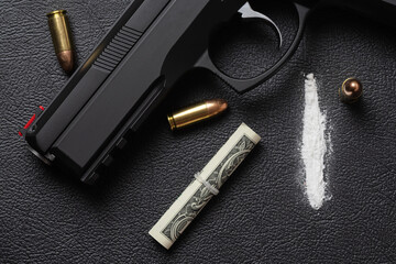 Dollar bill scroll, line of cocaine powder, 9 mm pistol and three full metal jacket bullets on black surface. Conceptual mockup of illegal drug dealing, criminal, trafficking or war on drugs. - obrazy, fototapety, plakaty