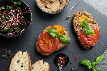 Obraz na płótnie Canvas Slices of bread with delicious pate, tomatoes and basil on grey table, flat lay