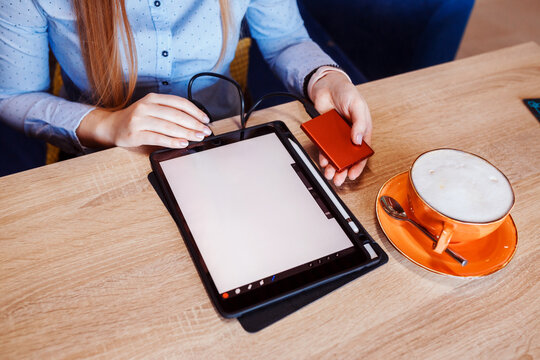 Woman is preparing to work on her tablet using external hard drive, cup of coffee next to her on the table. 