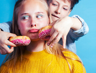 happy family brother and sister eating donuts on blue background, lifestyle people concept, boy and girl eating unhealthy food