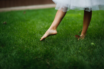 Slender tender female legs barefoot on the grass, close-up