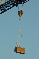 Rusty toolbox hanging off a construction crane attached by steel cable and hook