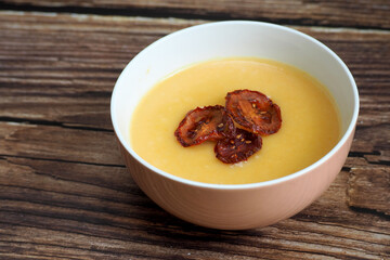 a round plate of vegetable soup mashed potatoes, carrots, onions, parsley root, a seller decorated with three chips of dried tomatoes stands on a brown wooden table. restaurant. cooking. gluten-free.
