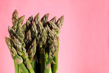a bunch of fresh green asparagus stands on a pink background. space for copying. vegan . healthy...