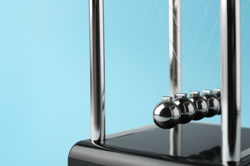 Newton's cradle on light blue background, closeup. Physics law of energy conservation