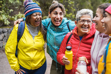 Multiracial women having fun during trekking day in mountain forest - Travel concept - Focus on african female face