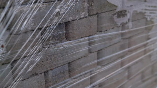 Stacked pack of grey brick for pavement. New pile of construction materials protected by cellophane. Close up.