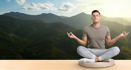 Fototapeta na wymiar Man practicing yoga on wooden surface against beautiful mountain landscape, space for text. Banner design