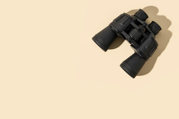 Binoculars black on a beige background. Top view, flat lay.