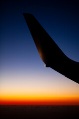 Ala de avión recortada contra el cielo en la puesta de sol