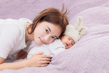 Single mom support and tenderly cuddles the newborn baby gently while the infant is sleeping on...