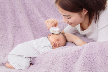 singlemom is combing her baby son hair with hair brush and baby care. while the son is sleeping, Young mother have happiness, Concept of hygiene and healthcare