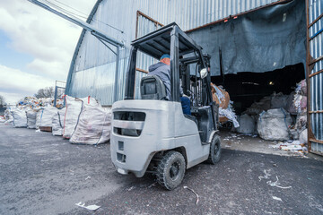 Forklift loading stack of paper and wastepaper into a paper recycling facility.