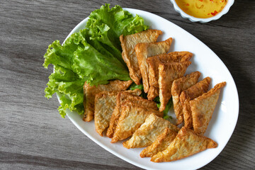 Triangular fried tofu eating with spicy dipping sauce, sweet and spicy