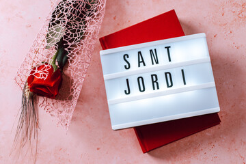 Red rose and red book on pink background, Sant Jordi holiday card