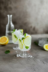 Two beautiful glasses with a cooling citrus drink. Lemonade with lemon, mint and crushed ice.