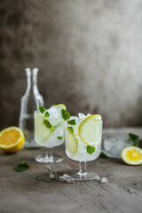 Two beautiful glasses with a cooling citrus drink. Lemonade with lemon, mint and crushed ice.