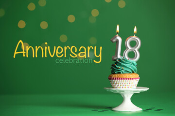 Coming of age party - 18th birthday. Delicious cupcake with number shaped candles on green background. Anniversary celebration