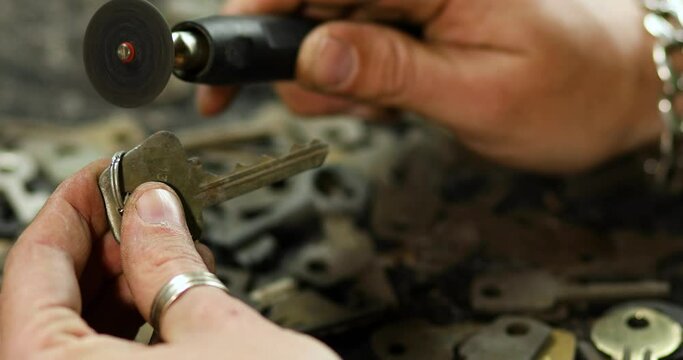 Locksmith in workshop makes new key, use grinding engraving machine, production of duplicate metal key.