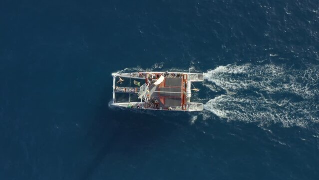 Aerial of catamaran sailing in sea ocean clear blue water. Group of people making ocean excursion trip tour. Catamaran sailboat cruising in sunset light view from above. Travel vacation concept