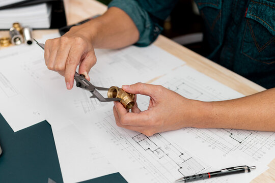 Close up hands of an engineer measures a metal part with Vernier caliper.