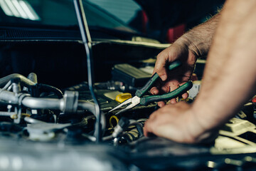 Auto mechanic working on car engine in mechanics garage.
