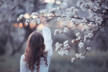 girl dreams back view, spring portrait happy girl in blooming garden, seasonal april
