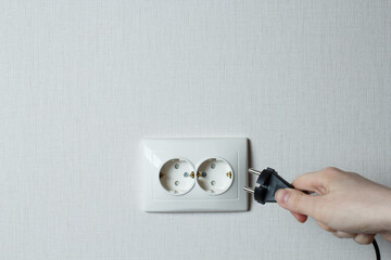 the girl inserts the electric plug into the socket.