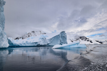 iceberg off the coast of Antarctic Peninsula against mountains and cloudy sky