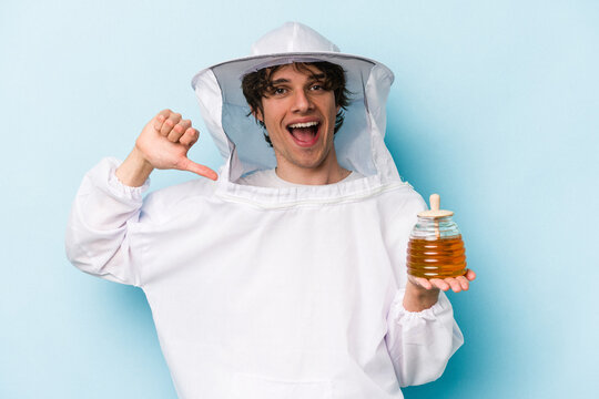 Young caucasian beekeeper man isolated on blue background feels proud and self confident, example to follow.