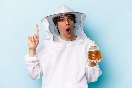 Young caucasian beekeeper man isolated on blue background having an idea, inspiration concept.