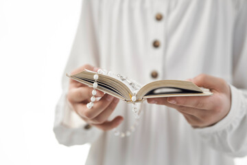 Girl in white dress holding a holy book with a rosary
