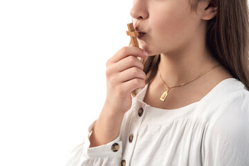 Girl in white dress holding and kissing a wooden crucifix