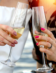 Two glasses of champagne in female hands, foreground. Friends are celebrating. Happiness. Holidays and events concept.
