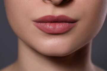 Woman with beautiful lips on grey background, closeup