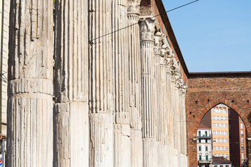 Ancient columns in a row at the famous historical site of Milan, Italy, named "Colonne di San Lorenzo" ("Saint Lorenzo's Columns"). Blue sky on the background.