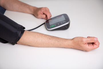  Man checking his blood pressure at home with a digital blood pressure monitor