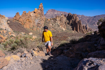 A young man on the descent path in the Roques de Gracia and the Roque Cinchado in the natural area...