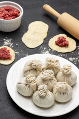 Raw khinkali dumplings on white plate.