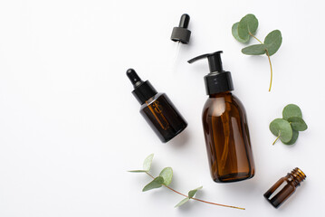 Natural cosmetics concept. Top view photo of glass bottles and eucalyptus on isolated white background with blank space
