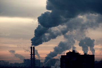 Smoke from chimneys over the evening city. Industrial city with bad ecology.