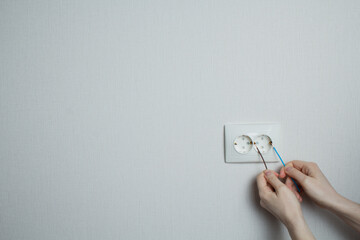 concept of what not to do. dangerous action. the girl inserts two wires into the socket.