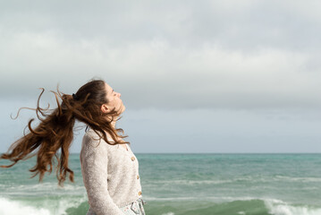 Fototapeta na wymiar Young woman moving her long ponytail with the breeze of the sea. Inspirational concept.