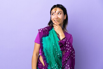 Indian woman isolated on purple background looking up while smiling