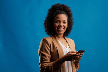 Portrait of happy african-american woman, holding her new phone, smiling for the picture.