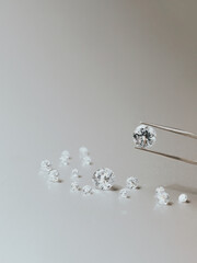 A round brilliant cut diamond held in tweezers - obrazy, fototapety, plakaty