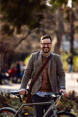 Portrait of a happy man, holding a bike in front of him, smiling at the camera.